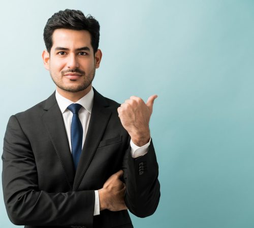 hispanic-male-executive-gesturing-copy-space-while-making-eye-contact-studio hispanic-male-executive-gesturing-copy-space-while-making-eye-contact-studio